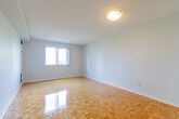 Located at 30 Elm Dr E in Mississauga, Ontario, this 2-bedroom, 1-bathroom unit offers a practical and well-organized layout throughout its single floor. Warm parquet flooring flows consistently through the main living areas and bedrooms, lending a classic character to the space.

The kitchen is efficiently designed with white cabinetry extending to the ceiling for ample storage, granite-look countertops, a double stainless steel sink, and a full-size Whirlpool refrigerator. The light-toned tile flooring keeps the kitchen area clean and distinct.

The primary bedroom is a generously sized room featuring a window with an outward view of the surrounding buildings and greenery, filling the space with natural light. It also benefits from access to a dedicated walk-in closet with built-in shelving, providing excellent storage. The second bedroom offers a similarly bright and open feel with the same parquet flooring.

The bathroom is finished in a clean, all-white palette, featuring a tiled tub-shower combination, a toilet, and a vanity with a granite-top countertop and under-sink storage. The tiled floor and bright white walls create a crisp, functional space.

A connecting hallway ties the rooms together seamlessly, with clean white walls and doors throughout maintaining a cohesive, bright aesthetic across the entire unit.
