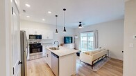 Located at 1737 Nicholasville Rd in Lexington, KY, this thoughtfully designed one-bedroom, two-bathroom unit offers a modern aesthetic with high-quality finishes throughout its efficient single-floor layout. The open-concept living area seamlessly connects the kitchen, dining, and living spaces, all tied together by warm light hardwood flooring and recessed lighting. The kitchen is a standout feature, boasting crisp white shaker cabinetry, granite countertops, a central island with an undermount sink, stainless steel appliances — including a refrigerator, range, and microwave — and sleek black pendant lighting overhead. The living room benefits from a ceiling fan, natural light from a large sliding glass door, and access to a private balcony. The generously sized bedroom features plush carpeting, a ceiling fan, a dedicated closet, and a window that lets in ample natural light. The two bathrooms are well-appointed with granite vanity tops and matte black fixtures, with one featuring a glass-enclosed walk-in shower. Additional practicalities include an in-unit laundry area, a utility room, and a pantry, ensuring functional storage and convenience throughout.