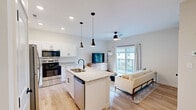 Located at 1737 Nicholasville Rd in Lexington, KY, this thoughtfully designed one-bedroom, two-bathroom unit offers a modern aesthetic with high-quality finishes throughout its efficient single-floor layout. The open-concept living area seamlessly connects the kitchen, dining, and living spaces, all tied together by warm light hardwood flooring and recessed lighting. The kitchen is a standout feature, boasting crisp white shaker cabinetry, granite countertops, a central island with an undermount sink, stainless steel appliances — including a refrigerator, range, and microwave — and sleek black pendant lighting overhead. The living room benefits from a ceiling fan, natural light from a large sliding glass door, and access to a private balcony. The generously sized bedroom features plush carpeting, a ceiling fan, a dedicated closet, and a window that lets in ample natural light. The two bathrooms are well-appointed with granite vanity tops and matte black fixtures, with one featuring a glass-enclosed walk-in shower. Additional practicalities include an in-unit laundry area, a utility room, and a pantry, ensuring functional storage and convenience throughout.