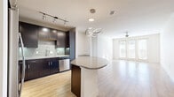 Located at 6215 Via la Cantera in San Antonio, TX, this well-appointed 3-bedroom, 5-bathroom residence offers a thoughtfully designed single-floor layout. The open-concept kitchen and living area serves as the heart of the home, featuring rich dark espresso cabinetry, a mosaic tile backsplash, stainless steel appliances, and a curved granite-topped island illuminated by a striking sculptural pendant light. Light wood-style flooring runs throughout the main living areas, enhancing the bright, airy atmosphere. The spacious living room is bathed in natural light through French doors that open to one of two balconies, and a ceiling fan adds to the comfort of the space. The primary bedroom is generously sized with plush carpeting, a ceiling fan, and access to a well-appointed en-suite bathroom featuring dark cabinetry, granite countertops, and clean tile flooring. Additional bedrooms are equally comfortable with soft carpeting and ceiling fans. Four closets, including walk-in options with built-in shelving, provide ample storage throughout. A dedicated in-unit laundry room with full-size washer and dryer hookups adds everyday convenience. With five bathrooms and two living and kitchen areas, this residence is designed to accommodate a variety of living arrangements.