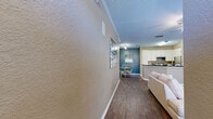 Located at 5009 Park Central Dr in Orlando, FL, this single-floor, 3-bedroom, 2-bathroom home offers a functional and well-appointed layout. The open-concept living, dining, and kitchen area forms the heart of the home, featuring rich dark hardwood-style flooring, crown molding, and a ceiling fan with light fixture in the living room, which receives natural light through large windows dressed with blinds and sheer curtains. The kitchen is equipped with stainless steel appliances, white cabinetry, dark granite-style countertops, and a peninsula that connects seamlessly to the dining area, which is accented by a bold blue feature wall. The three bedrooms offer carpeted flooring and ceiling fans, with the primary bedroom providing a comfortable, private retreat. The secondary bedrooms are versatile, with one featuring tile floors and natural light suited for use as a home office. Both bathrooms include tile flooring; one features a shower-tub combination, while the other offers a vanity with dark countertops and an adjacent closet. Two hallways and a dedicated entrance connect the rooms efficiently. The warm, neutral color palette and consistent finishes throughout create a cohesive and inviting atmosphere.