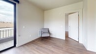 This well-designed 810-square-foot apartment offers 2 bedrooms and 2 bathrooms across a single floor, combining modern finishes with a functional layout. The kitchen is a standout feature, outfitted with gray shaker-style cabinetry, a white subway tile backsplash, open wood floating shelves, light quartz countertops, and a full suite of stainless steel appliances including a refrigerator, range, microwave, and dishwasher. Light hardwood-style flooring runs consistently throughout the entire unit, creating a cohesive and clean aesthetic. The living room opens directly to a private balcony through large black-framed sliding glass doors, flooding the space with natural light and providing open outdoor views of the surrounding neighborhood. The primary bedroom measures 150 square feet and includes large windows with roller shades, a closet, and the same light flooring. The second bedroom is equally bright, with a generous window offering additional outdoor views. Both bathrooms are finished with gray vanities, white quartz countertops, chrome fixtures, and full tub-shower combinations. The unit's neutral color palette and contemporary design details create a bright, modern living environment throughout.