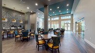 Located at 3640 Mapleshade Ln in Plano, Texas, this single-floor community amenity space is designed with a sophisticated and cohesive aesthetic throughout. The expansive dining area serves as the centerpiece, boasting soaring ceilings, a striking teal ceiling accent, and herringbone-patterned wood flooring. Tall windows flood the space with natural light and offer views of the outdoor pool courtyard. Upholstered chairs in teal and gold surround wooden dining tables, creating an inviting and refined atmosphere.

Adjacent to the dining area, a glass-enclosed private dining or meeting room features elegant chandelier lighting, a large round mirror, and a formal table arrangement—ideal for gatherings or events. A dedicated game room offers a billiards table, wall-mounted TV, large aquarium, and patterned carpet beneath a dark ceiling, giving it a distinct, entertainment-focused character.

A cozy lounge area with a bold teal-and-gold color palette, wicker sofa, and direct access to the outdoor pool area provides a relaxed retreat. Additional seating nooks with curated artwork and soft furnishings in navy and yellow offer quiet spaces throughout. A well-appointed kitchenette with granite countertops, dark cabinetry, and a beverage station rounds out the amenities, completing this thoughtfully designed communal facility.