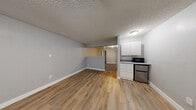 Located at 4505 Paradise Rd in Las Vegas, Nevada, this one-bedroom, one-bathroom unit offers a practical and efficient single-floor layout. The open-concept living, dining, and kitchen area is finished with warm wood-look luxury vinyl plank flooring and neutral gray walls, creating a clean, cohesive aesthetic. A textured popcorn ceiling adds a classic touch throughout the main living space. The compact kitchen is outfitted with white cabinetry, granite-style countertops, a stainless steel mini-refrigerator, and a microwave, making efficient use of the available space. The bedroom is carpeted for comfort and features two separate closets, offering notable storage capacity relative to the unit's overall footprint. Gray walls and a textured ceiling continue into the bedroom, maintaining a consistent design language. The bathroom includes a white vanity with a round undermount sink set atop granite-style countertops, a tub/shower combination with a sliding glass door, and wood-look flooring that ties back to the main living area. Clean white walls and ample lighting give the bathroom a bright, functional feel. Overall, the unit presents a well-maintained, move-in-ready space with consistent finishes throughout.
