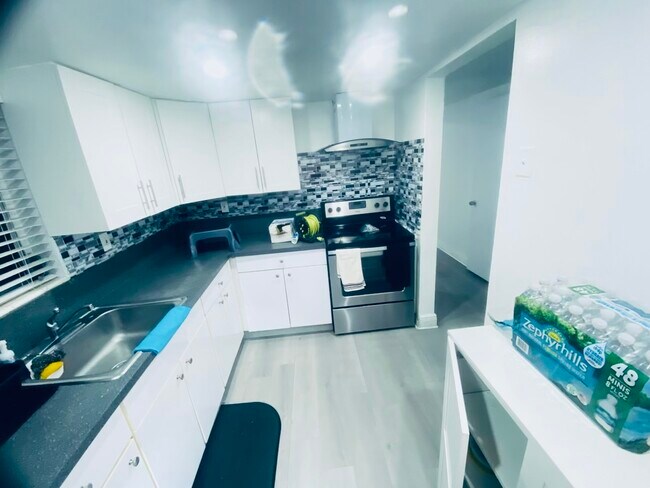 Full kitchen with stainless steel stoce and overhead hood with light, beautiful backsplace - 10901 N Kendall Dr