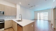 Located at 40 William St in Wellesley Hills, MA, this thoughtfully designed one-bedroom, two-bathroom residence offers a clean, contemporary aesthetic throughout. The open-concept kitchen and living area serves as the heart of the home, featuring warm hardwood flooring, recessed lighting, and large sliding glass doors that invite abundant natural light into the living room. The kitchen is outfitted with flat-front cabinetry in a light wood finish, a tile backsplash, stainless steel appliances including a side-by-side refrigerator and range, and a central island with a white quartz countertop and built-in sink — ideal for both cooking and casual dining. A hallway finished with large-format marble-look porcelain tile connects the main living spaces to the private quarters. The bedroom is carpeted for comfort, features a generous window with exterior views, and includes access to a dedicated closet as well as built-in shelving — a practical touch for storage and organization. Both bathrooms continue the marble-tile aesthetic, with one featuring a full soaking tub and tiled surround. The overall palette of crisp whites and natural wood tones creates a bright, cohesive, and welcoming atmosphere throughout.