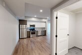 Located at 100 Hemenway Street, Unit 206 in Boston's Fenway neighborhood, this three-bedroom, two-bathroom residence offers a thoughtfully designed single-floor layout with modern finishes throughout. The open-concept kitchen, dining, and living area serves as the heart of the home, featuring light wood-tone flooring, recessed lighting, and a sleek kitchen equipped with stainless steel appliances — including a refrigerator, gas range, microwave, and dishwasher. White upper cabinetry contrasts with warm taupe lower cabinets and light stone countertops, giving the space a clean, contemporary aesthetic. Each of the three bedrooms is finished with neutral carpet, soft gray walls, and window blinds that allow for natural light and privacy. The primary bedroom includes a wall-mounted mini-split HVAC unit for individual climate control. Closets are generously distributed throughout, with five total across the unit. The bathrooms are finished with large-format gray tile flooring, white Shaker-style doors with matte black hardware, and warm wood-toned vanities paired with white countertops. The consistent use of neutral tones and modern materials throughout creates a cohesive, move-in-ready living environment well-suited for urban Boston living.