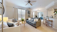 This thoughtfully designed one-bedroom, one-bathroom residence in Carrollton, TX offers a comfortable and efficient single-floor layout. The open-concept living area is bright and welcoming, featuring plush carpeting, crown molding, and a ceiling fan, with multiple windows dressed in elegant drapes that invite generous natural light. The space flows seamlessly into a separate dining area, distinguished by a stylish chandelier and an arched architectural detail that adds a refined touch. A dedicated sitting nook with its own ceiling fan and large window provides a versatile secondary retreat. The kitchen features tile flooring, warm honey-toned cabinetry, black appliances including a refrigerator, range, and built-in microwave, complemented by a tile backsplash. The primary bedroom is a calm, well-proportioned retreat with a window overlooking the outdoors and soft carpet underfoot. It is served by a walk-in closet outfitted with wire shelving for ample storage. The full bathroom includes a wide vanity with white cabinetry, a granite-style countertop, a large mirror, and tile flooring. Throughout the residence, neutral tones and consistent finishes create a cohesive, comfortable ambiance ideal for everyday living.