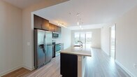 This single-floor unit showcases a thoughtfully designed open-concept layout that seamlessly connects the kitchen, dining, and living areas. The kitchen is outfitted with rich dark-toned cabinetry, granite countertops, and a full suite of stainless steel appliances, including a French door refrigerator, electric range, and built-in microwave. A central island with an integrated sink and pendant lighting above serves as both a functional workspace and a natural dividing point between the kitchen and the expansive living area. Light wood-style flooring runs throughout the main living spaces, complementing the neutral wall tones and contributing to a clean, contemporary aesthetic. The living area is bathed in natural light, thanks to large floor-to-ceiling windows and sliding glass doors that open to a balcony offering elevated city and treetop views. The bedroom is carpeted and similarly benefits from floor-to-ceiling glass doors with outdoor access and abundant natural light. The bathroom features tile flooring, a combination tub and shower, and granite-topped vanity. A hallway houses a stacked in-unit washer and dryer for added convenience.