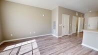 Located on East Street in Clinton, Mississippi, this single-floor unit offers a well-designed, efficient layout across its compact footprint. The open-concept kitchen and living area forms the heart of the space, filled with natural light streaming through large windows that cast warm patterns across the wood-look luxury vinyl plank flooring found throughout.

The kitchen is outfitted with stainless steel appliances, including a range, over-the-range microwave, refrigerator, and dishwasher. Crisp white shaker-style cabinetry pairs with light quartz countertops and a classic subway tile backsplash, while a double-basin stainless steel sink with a brushed nickel faucet adds a refined touch. The living area is spacious enough for comfortable furnishing and benefits from the same neutral warm-beige wall tones that carry throughout the unit.

The bathroom features a white vanity with quartz countertop, an undermount sink, and brushed nickel hardware, complemented by tile flooring for a clean, functional finish. Adjacent to the bathroom, the dedicated laundry area includes a full-size top-loading washer and dryer with built-in overhead shelving, offering added convenience and storage. The overall design is modern, clean, and move-in ready.