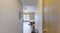 Located at 420 S Chauncey Ave in West Lafayette, Indiana, this one-bedroom, one-bathroom unit offers an efficient single-floor layout designed to maximize every square foot. The living area flows directly into a functional kitchen equipped with a gas range, microwave, and light wood cabinetry that provides ample storage. The kitchen's open configuration connects seamlessly to the main living space, creating a practical, multi-use area finished with hardwood-style flooring that runs throughout the unit.

The generously proportioned bedroom is the standout feature of this unit, occupying the majority of the total floor area. It is outfitted with a ceiling fan with light fixture and features large sliding glass doors that invite natural light and provide outdoor access, contributing to an open, airy feel. A wall-mounted air conditioning unit also serves the space.

The bathroom is accessible via a short hallway and includes a full bathtub and shower combination with a curtain rod, a single-sink vanity with wood cabinetry, and a toilet, all finished with the same hardwood-style flooring. The textured ceilings and warm-toned wood door frames give the unit a consistent, cohesive aesthetic throughout.
