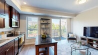 Located in the heart of Saint Paul, this single-floor communal amenity space offers a refined blend of modern design and warm, inviting finishes. The interior lounge is anchored by rich hardwood flooring and striking exposed wooden ceiling beams that lend a sense of architectural character throughout. A fully equipped kitchenette lines one wall, featuring dark wood cabinetry, white quartz countertops, a beverage refrigerator, a sink, and a geometric patterned tile backsplash — all framed by a wall-mounted flat-screen TV overhead. Elegant pendant lighting illuminates a central island with seating, creating a natural gathering point for socializing. Wainscoting in a muted sage-green palette adds a sophisticated, layered look to the walls. A windowed nook area with high-top tables and bar stools offers views of the surrounding cityscape, while French doors open to a spacious rooftop terrace. The outdoor deck is thoughtfully appointed with Adirondack chairs surrounding a fire pit, an outdoor dining table, a gas grill, and an exterior television — all set against panoramic views of downtown Saint Paul. This versatile space is ideal for hosting events or relaxing in an upscale urban setting.
