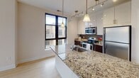 Located at 10914 Georgia Ave in Silver Spring, Maryland, this well-designed single-floor residence offers a thoughtful layout with a clean, contemporary aesthetic. The kitchen is a standout feature, showcasing high-gloss white upper cabinetry, dark lower cabinets, granite countertops, and a full suite of stainless steel appliances including a refrigerator, electric range, and built-in microwave. Pendant lighting and track lighting illuminate the space, while light hardwood-style flooring and a large window overlooking the surrounding neighborhood add brightness and depth. A generous kitchen island with granite countertop provides additional workspace and casual seating. The bedrooms are spacious and comfortable, each finished with plush wall-to-wall carpeting and large windows that invite natural light and offer views of the neighboring architecture. A carpeted hallway with clean white panel doors connects the private areas of the home. The bathrooms are tastefully finished with granite vanity countertops, tile flooring, and full tub/shower combinations. One bathroom features a tiled surround soaking tub, while a second full bath offers a shower with a large vanity mirror. The overall ambiance is modern, clean, and move-in ready, reflecting a consistent design language of neutral tones and quality finishes throughout.