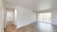 This single-floor residence offers a well-organized layout that balances functional living spaces with comfortable design. The galley-style kitchen is outfitted with warm wood cabinetry, granite-look countertops, a double-basin stainless steel sink, and white appliances including an electric range, dishwasher, and refrigerator. Ample upper and lower cabinet storage lines both sides of the kitchen, maximizing utility in the space.

The living area is a standout feature, highlighted by a full brick accent wall with a wood-burning fireplace that serves as a natural focal point. A sliding glass door with vertical blinds allows natural light to filter in while providing outdoor access. The hardwood-style flooring throughout the main living areas adds warmth and continuity to the space.

Two bathrooms serve the residence. One features a full bathtub and vanity with ample counter space, while the second offers a walk-in shower with mosaic tile flooring and clean white tile surround, accented by chrome fixtures and grab bars. Both bathrooms continue the hardwood-style flooring found throughout the home.

A carpeted bedroom provides a soft, quiet retreat, and an electrical panel is conveniently accessible in the hallway. The overall aesthetic is clean and neutral, offering a versatile canvas for personalization.