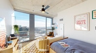 Located at 1114 West Carroll Avenue in Chicago's vibrant West Loop neighborhood, this one-bedroom, one-bathroom unit offers a thoughtfully designed layout that maximizes every square foot. The space is defined by striking exposed concrete ceilings throughout, lending an industrial-modern aesthetic that anchors the overall design.

The galley-style kitchen features sleek white cabinetile cabinetry extending to the ceiling, stainless steel appliances including a gas range, built-in microwave, and full-size refrigerator, complemented by a slate blue subway tile backsplash and light stone countertops. Checkered flooring adds a playful design touch in the kitchen corridor.

The bedroom is a standout space, offering generous proportions and dramatic floor-to-ceiling windows that bathe the room in natural light and frame expansive views of the Chicago skyline. A ceiling fan adds comfort, while warm hardwood flooring and a cozy, eclectic aesthetic complete the room. The living area extends to a sun-filled corner with large-format windows offering additional panoramic city views.

The bathroom is well-appointed with a walk-in glass shower featuring white tile, matte black fixtures, a vanity with ample storage, and a large mirror. A dedicated in-unit laundry closet houses a stacked full-size washer and dryer, adding everyday convenience to this efficiently designed urban residence.