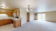 Located at 1951 Scheuring Rd in De Pere, Wisconsin, this single-floor, 2-bedroom, 2-bathroom home offers a well-organized and functional layout. The open-concept kitchen and living room serve as the heart of the home, where warm oak cabinetry, tile flooring, and white appliances define the kitchen space. A chandelier adds a classic touch above the dining area, while the living room features plush carpeting and a sliding glass door that fills the space with natural light and provides access to the outdoors. Both bedrooms are carpeted and finished with neutral tones, offering comfortable, quiet retreats. The generously sized primary bedroom connects to a full bathroom equipped with a glass-door shower, an oak vanity with a wide mirror, and tile flooring. A well-appointed walk-in closet with built-in shelving and hanging rods provides excellent storage. The second bathroom features a full tub-shower combo and a matching oak vanity. Additional highlights include a utility room, two closets, and an attached garage with an automatic opener. Baseboard heating is present throughout, ensuring comfort during Wisconsin winters. The overall aesthetic is clean and understated, with consistent warm wood trim and neutral wall tones unifying every room.