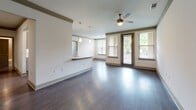 Located on Ronald Reagan Boulevard in Alpharetta, Georgia, this single-floor residence offers a well-designed layout that balances open living with functional spaces. The interior is unified by rich, dark hardwood-style flooring that flows seamlessly throughout every room, complemented by crisp white walls and elegant crown molding with distinctive green-toned accents.

The open living area is bright and inviting, featuring a ceiling fan, multiple windows with blinds that draw in generous natural light, and a glass-paneled door that provides views of the surrounding greenery. A pass-through counter with pendant lighting connects the living space to the kitchen, creating an open and sociable flow.

The kitchen is well-appointed with stainless steel appliances, including a refrigerator and range, sleek cabinetry with modern hardware, light-toned countertops, and a decorative wine rack above the upper cabinets. An adjacent nook offers additional storage or utility space.

The bedroom is a quiet, comfortable retreat with a ceiling fan, a large window overlooking outdoor greenery, and the same consistent flooring and crown molding details found throughout the home.

The bathroom features wood-toned cabinetry with granite countertops and includes a tub-shower combination with tiled walls, offering both style and practicality. The hallway provides access to a closet, enhancing overall storage capacity. This residence combines modern finishes with a cohesive, welcoming design.