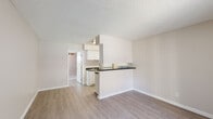 Located at 5111 N Mesa St in El Paso, TX, this single-story, one-bedroom, two-bathroom unit offers a practical and efficiently designed floor plan. The living area greets you at the entry with light hardwood-style flooring, neutral warm-toned walls, and a textured ceiling that carries throughout the unit. A wall-mounted air conditioning unit keeps the space comfortable year-round.

The kitchen flows directly off the living space in an open-concept layout, featuring a peninsula counter with a dark contrasting countertop, white cabinetry above and below, and a sink — offering a functional workspace while maintaining visual connectivity with the living area.

The bedroom is carpeted for warmth and comfort, bathed in natural light through a large window fitted with vertical blinds, and equipped with a ceiling fan. Notably, the bedroom features dual closets with sliding doors and double hanging rods, providing generous storage capacity relative to the room's size.

The unit includes two bathrooms: one with a clean white vanity, cabinet storage, a large mirror, and hardwood-style flooring; and a second with a full tub-shower combination with white tile surround. Both bathrooms maintain a clean, bright, and minimalist aesthetic consistent with the rest of the unit.