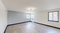 Located at 1201 Heeney Avenue in Johnstown, PA, this single-floor, 2-bedroom, 1-bathroom unit offers a clean, modern aesthetic with thoughtful updates throughout. Light-toned vinyl plank flooring runs continuously across the living spaces, complemented by crisp white walls, bold dark baseboards, and contemporary lighting fixtures that create a fresh, cohesive look.

The living room is a comfortable, open space bathed in natural light from corner windows fitted with blinds. The kitchen features grey shaker-style cabinetry, light marble-look countertops, a double stainless steel sink with a modern faucet, and black appliances including a refrigerator and electric range. A pass-through opening connects the kitchen to the adjacent living area, enhancing the open feel.

The primary bedroom is generously sized, with corner windows allowing ample natural light and outdoor views. The second bedroom is well-proportioned, also featuring a window with blinds. Both rooms offer access to closet storage, with four closets distributed throughout the unit — providing excellent organization options.

The bathroom is neatly appointed with a navy blue vanity, white countertop, a tub-shower combination, and a window for natural ventilation. A utility room and two hallways round out the layout, ensuring functional flow throughout. The unit presents a move-in ready, updated living space.