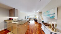 Located at 230 First Ave in Boston's Charlestown neighborhood, this well-designed three-bedroom, three-bathroom residence offers a thoughtful layout across a single floor. The open-concept living and dining area serves as the heart of the home, showcasing rich hardwood flooring that flows seamlessly throughout. Large windows flood the living space with natural light and provide views of the surrounding neighborhood, creating a bright and welcoming atmosphere. The kitchen features granite countertops, warm wood cabinetry, and a functional island with seating, connecting effortlessly to the dining and living areas. The primary bedroom is a comfortable retreat with plush carpeting, dual windows, and a serene, neutral palette. The two additional bedrooms are equally well-appointed with soft carpeting and tasteful finishes, each offering ample closet space. The three bathrooms are clean and modern — one features large-format travertine tile surrounding a soaking tub and a separate glass shower, while another offers classic white subway tile with a tub-shower combination. Warm beige tones and stone-topped vanities complete the bathrooms' refined look. A hallway and dedicated closet round out the efficient and comfortable floor plan of this Boston residence.