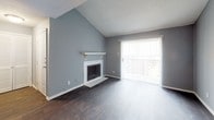 This single-floor, 1-bedroom, 1-bathroom unit offers a thoughtfully designed layout that maximizes comfort and functionality. The living room is a standout space, featuring dramatic vaulted ceilings with a textured finish, dark hardwood-style flooring, and a classic wood-burning fireplace with a white mantel and tile surround. A large sliding glass door floods the room with natural light and provides outdoor access. Adjacent to the living area, the galley-style kitchen is well-equipped with white shaker cabinetry, granite countertops, a stainless steel sink, and black appliances including a refrigerator, range, microwave, and dishwasher. Track lighting overhead enhances the kitchen's functionality. The bedroom is generously sized, featuring soft wall-to-wall carpeting, a ceiling fan with light fixture, a walk-in closet, and a window that brings in natural light. Consistent cool-toned gray walls flow throughout the unit, creating a cohesive and modern aesthetic. The overall layout is efficient and open, making excellent use of the available space while maintaining a clean, move-in-ready presentation.