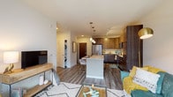 This well-appointed single-floor residence features a thoughtfully designed open-concept layout that seamlessly connects the kitchen, dining, and living areas. The kitchen is a standout feature, showcasing rich two-tone cabinetry in warm walnut and dark espresso finishes, a full suite of stainless steel appliances including a refrigerator, range, and microwave, a subway tile backsplash, and a central island with a light quartz countertop that doubles as a dining bar with seating. Pendant lighting and track lighting illuminate the space effectively. Wood-look plank flooring runs throughout the main living areas, adding warmth and continuity.

The living area is generously proportioned and opens directly to a private balcony through a full-width sliding glass door, allowing natural light to flow in and providing outdoor views of the surrounding community. A dedicated in-unit laundry closet with a stacked washer and dryer is conveniently located near the main living space.

The bedroom is comfortably sized with plush carpeting, a ceiling fan, large windows that bring in natural light, and a spacious walk-in closet with built-in shelving. The bathroom features a sliding-door walk-in shower, light wood-look tile flooring, and clean, neutral finishes throughout.