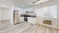 This 410 square foot apartment in Los Angeles offers a well-designed living space with modern amenities. The single-floor layout comprises one bedroom, one bathroom, and an open-concept kitchen area. The kitchen is a standout feature, boasting sleek white cabinetry, stainless steel appliances including a full-size refrigerator and gas range, and ample counter space. Light-toned wood-look flooring runs throughout the apartment, creating a cohesive and contemporary aesthetic.

The bedroom, measuring 140 square feet, is generously sized for the overall apartment footprint. It features a large window allowing natural light to flood the space and includes a mirrored closet door, maximizing the sense of spaciousness. The bathroom, while compact, is efficiently designed with a single vanity, toilet, and shower/tub combination.

The apartment's design emphasizes brightness and airiness, with white walls and ceilings complementing the light flooring. Windows in each room provide natural illumination and views to the outside. The unit also includes modern conveniences such as recessed lighting and a ceiling fan. Located at 833 S Berendo St in Los Angeles, this apartment combines functionality with style in a compact urban living space.
