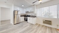 This 410 square foot apartment in Los Angeles offers a well-designed living space with modern amenities. The single-floor layout comprises one bedroom, one bathroom, and an open-concept kitchen area. The kitchen is a standout feature, boasting sleek white cabinetry, stainless steel appliances including a full-size refrigerator and gas range, and ample counter space. Light-toned wood-look flooring runs throughout the apartment, creating a cohesive and contemporary aesthetic.

The bedroom, measuring 140 square feet, is generously sized for the overall apartment footprint. It features a large window allowing natural light to flood the space and includes a mirrored closet door, maximizing the sense of spaciousness. The bathroom, while compact, is efficiently designed with a single vanity, toilet, and shower/tub combination.

The apartment's design emphasizes brightness and airiness, with white walls and ceilings complementing the light flooring. Windows in each room provide natural illumination and views to the outside. The unit also includes modern conveniences such as recessed lighting and a ceiling fan. Located at 833 S Berendo St in Los Angeles, this apartment combines functionality with style in a compact urban living space.