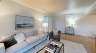 This single-floor residence offers a thoughtfully designed layout that balances comfort and functionality throughout. The living room features crown molding, a structural ceiling beam, and a sliding glass door with vertical blinds that invite natural light and provide access to the outdoors. Soft carpet flooring and a neutral color palette create a warm, inviting atmosphere.

The kitchen is outfitted with white shaker-style cabinetry, light quartz countertops, a stainless steel sink with a modern faucet, and wood-look plank flooring. A window above the counter fills the space with natural light, while stainless steel appliances and a dishwasher complete the functional setup.

The dining area is defined by a tray ceiling and wood-look flooring, lending it a distinct, elegant character. The bedroom features plush carpet, multiple windows, and a sliding glass door allowing for ample natural light. An adjacent vanity area with white cabinetry and a large mirror provides generous storage and prep space.

The bathroom includes a full soaking tub with marble-style surround walls and wood-look flooring. A dedicated laundry area houses a stacked washer and dryer unit, adding everyday convenience. Throughout, the design maintains a cohesive, neutral aesthetic with modern finishes.