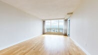 Located at 7307 Campeau Dr in Ottawa's Kanata neighbourhood, this 2-bedroom, 2-bathroom unit offers a well-designed single-floor layout with a clean, contemporary aesthetic throughout. Light hardwood flooring flows seamlessly across the living areas and bedrooms, contributing to a bright and cohesive feel.

The spacious living room is a standout feature, anchored by expansive floor-to-ceiling windows and a sliding glass door that frame sweeping panoramic views of the Ottawa cityscape, flooding the space with natural light. The kitchen is efficiently designed with white shaker-style cabinetry, grey countertops, a classic white subway tile backsplash, and stainless steel appliances including a range, microwave, and dishwasher. A breakfast bar provides additional counter space and connectivity to the living area.

Both bedrooms are comfortably sized with hardwood floors and neutral tones, offering a calm and restful atmosphere. The primary bedroom benefits from generous proportions. The two bathrooms are finished with light tile flooring and white subway tile surrounds — one featuring a soaker tub and shower combination, and the other a sleek glass-enclosed walk-in shower, both appointed with brushed nickel fixtures.
