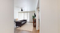 Located at 210 S Avenida del Convento in Tucson, AZ, this thoughtfully designed two-bedroom, one-bathroom unit offers a smart and functional single-floor layout. The living room serves as the heart of the home, featuring warm wood-look flooring, a ceiling fan with light, and large floor-to-ceiling windows with blinds that invite abundant natural light. A glass patio door opens to an outdoor balcony area, extending the living space further. The kitchen is a standout feature, showcasing white shaker cabinetry reaching to the ceiling, a subway tile backsplash, stainless steel appliances including a range and refrigerator, a deep undermount sink with a commercial-style faucet, and a peninsula with bar seating illuminated by industrial-style pendant lighting. The two bedrooms are carpeted for comfort, each with a ceiling fan and windows fitted with blinds. The primary bedroom offers a generous footprint with a closet. The shared full bathroom is clean and bright, featuring a white vanity with quartz countertop, a frameless mirror, sconce lighting, and a shower with curtain. Carpeted hallways connect the private areas of the home, and the overall palette of crisp white walls and neutral tones creates a calm, cohesive ambiance throughout.