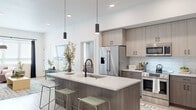Located at 146 S Wayfinder Ave in Meridian, Idaho, this single-story home showcases a clean, contemporary design with an open-concept floor plan and cohesive modern aesthetic throughout. Light wood-tone flooring runs consistently across the main living areas, complementing the bright white walls and creating a warm, airy atmosphere.

The kitchen serves as the centerpiece of the home, featuring a generously sized island with a white quartz countertop, an undermount sink with a matte black faucet, and seating for multiple guests via sage green bar stools. Two sleek pendant lights hang above the island, adding a refined touch. Two-tone cabinetry in a warm gray-brown finish pairs with subway tile backsplash, and stainless steel appliances—including a French door refrigerator, electric range, and built-in microwave—complete the space.

The living room offers a comfortable, well-lit retreat with natural light filtering through windows dressed in layered roller shades and dark curtains. The bedroom spaces are thoughtfully designed, with the primary suite featuring high clerestory windows and access to a walk-in closet area. A secondary bedroom provides natural light through a large window. The bathroom includes a tub-shower combination, wood-tone vanity, white quartz countertop, and a backlit mirror with matte black fixtures throughout.