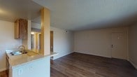 This single-floor unit offers a well-organized, open layout that connects the main living and dining areas to the kitchen seamlessly. The living room features warm wood-style flooring, neutral-toned walls, a ceiling fan, and a textured ceiling. A sliding glass door with vertical blinds opens to a private balcony, bringing in natural light and outdoor views. The kitchen is efficiently designed in a galley style, showcasing rich wood cabinetry, light granite-style countertops, white appliances including a range and refrigerator, and a peninsula with a built-in sink that faces the living area — ideal for casual dining or entertaining. The primary bedroom is generously sized, also featuring wood-style flooring and a vanity area with a granite-topped cabinet and lighted mirror. A secondary bedroom includes a wide closet with sliding doors, providing ample storage, as well as a window with natural light. The full bathroom is clean and functional, featuring a combined tub and shower with chrome fixtures. Consistent wood-style flooring, textured ceilings, and neutral tones throughout the unit create a cohesive and practical living environment.