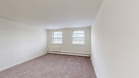 Located at 101 W Baltimore Pike in Lansdowne, PA, this one-bedroom, one-bathroom unit offers a practical and well-organized single-floor layout. The living room is generously sized, featuring neutral carpet flooring, cream-toned walls, and dual windows that bring in natural light while offering views of the surrounding neighborhood. Baseboard heating runs throughout the carpeted areas, ensuring consistent warmth. The kitchen is efficiently designed with warm wood-toned cabinetry, dark countertops, a double sink, and wood-look vinyl flooring. White appliances, including a refrigerator and electric range, are included. Adjacent to the kitchen, the dining area provides a defined space for meals. The bedroom is a comfortable size, featuring two side-by-side closets, multiple windows for natural light, and the same soft carpet found throughout the living areas. Additional closets are accessible via the hallway, offering ample storage. The bathroom is clean and functional, with a white vanity with cabinet storage, a medicine cabinet mirror with overhead lighting, and tile flooring. Overall, the unit presents a bright, neutral palette with a straightforward layout suited for everyday living.