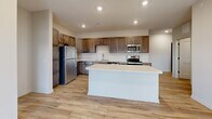 Located at 1220 W Highland Blvd in Lincoln, Nebraska, this two-story home offers 2 bedrooms and 3 bathrooms across a well-designed layout. The main living level hosts a thoughtfully arranged kitchen equipped with rich, dark-stained wood cabinetry, light quartz countertops, and a full suite of stainless steel appliances including a refrigerator, range, microwave, and dishwasher. Light hardwood-style flooring runs throughout the main living areas, lending a warm, cohesive feel. A staircase connects the levels, with the upper floor comprising the majority of the living space. The bedrooms feature plush carpet flooring, ceiling fans, and window blinds for comfort and privacy. The primary bedroom includes access to a private balcony through sliding glass doors, offering an outdoor retreat. Three well-appointed closets, including a walk-in with built-in shelving and hanging rods, provide ample storage. The bathrooms feature light hardwood-style flooring, vanities with quartz countertops, and tub-shower combinations. A dedicated in-unit laundry room accommodates a full-size washer and dryer. The attached garage features a concrete floor and direct interior access, completing this functional and modern home.