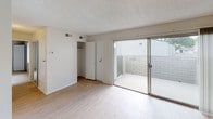 This single-floor residential unit presents a clean, functional layout across several well-defined living spaces. The main living area features light wood-style flooring and a ceiling fan, creating a bright, airy atmosphere well-suited for everyday living and relaxing. A textured popcorn ceiling runs throughout, adding a classic residential character to the space.

The kitchen is efficiently arranged with white cabinetry, a gas range, a full-size refrigerator, and granite-style countertops that extend to a dedicated workspace — providing ample room for meal preparation. The kitchen flows naturally into the rest of the unit through an open corridor layout.

A carpeted bedroom offers a quiet retreat, while a secondary room with light wood flooring includes a built-in closet and sliding glass doors that open directly onto a private enclosed patio with brick privacy walls, bringing in natural light.

The bathroom is well-appointed with a granite-style undermount sink, bright vanity lighting, a large mirror, and convenient access to additional storage areas with open shelving, ideal for organization.

Throughout the unit, neutral tones on the walls complement the light flooring, creating a cohesive and versatile palette ready for personalization. The space is thoughtfully designed to balance practicality with comfortable everyday living.