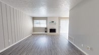 Located at 209 Hal Muldrow Dr in Norman, Oklahoma, this two-story home presents a clean, neutral aesthetic throughout its well-maintained interior. The living room serves as a central gathering space, showcasing wood-look laminate flooring, a textured ceiling, and a white brick fireplace with a raised hearth and decorative mantel shelf. Vertical blinds cover a sliding glass door that allows natural light to flow in, complementing the windows fitted with horizontal blinds along one wall, which features vertical shiplap-style paneling for added character.

The kitchen is equipped with white cabinetry, granite-style countertops, a stainless steel range, and a double-basin sink. A bold mosaic tile backsplash in earth tones adds a distinctive visual element to the space. Tile flooring carries through this functional area seamlessly.

The bedrooms are carpeted and finished in soft gray tones, each featuring a ceiling light fixture and windows that provide natural light. The bathrooms include white cabinetry with granite-style counters, a framed mirror, tile flooring, a glass-enclosed shower stall, and clean, functional fixtures throughout. The overall ambiance of the home is light, neutral, and move-in ready.
