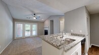 Located at 7889 Roswell Rd in Sandy Springs, GA, this single-floor residence offers a well-designed open layout that maximizes both functionality and comfort. The living area is distinguished by soaring vaulted ceilings and a classic fireplace with a white mantel, creating a warm and inviting focal point. Plush carpeting runs throughout the living and bedroom spaces, while durable hardwood-style flooring anchors the kitchen area.

The kitchen is a standout feature, equipped with granite countertops, white cabinetry, stainless steel appliances including a gas range, microwave, refrigerator, and dishwasher, as well as a peninsula with a double stainless steel sink — ideal for both cooking and casual dining. Track lighting illuminates the workspace efficiently.

The bedroom features vaulted ceilings, a ceiling fan, and a large window with outdoor views, providing ample natural light. French doors in the living area open to a private balcony, further enhancing the connection to the outdoors. A dedicated laundry area with a washer is conveniently tucked within the unit. The bathroom includes a full tub-shower combo with clean white tile surround. The overall neutral color palette and open flow create a bright, move-in-ready environment throughout.