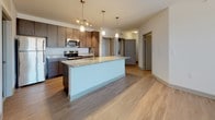 Located at 100 Whitworth Way in Williamsburg, Virginia, this single-floor residence offers a well-designed, open-concept layout with modern finishes throughout. The living area features light hardwood-style flooring, neutral walls, and ceiling fans, creating a bright and airy atmosphere. Multiple windows fitted with blinds allow generous natural light to flow through the space while offering views of the surrounding neighborhood.

The kitchen is a standout feature, equipped with dark espresso cabinetry, granite countertops, stainless steel appliances including a range, microwave, and refrigerator, and a peninsula island with pendant lighting overhead. This space connects seamlessly to the open living area, making it ideal for both daily living and entertaining.

The bedrooms are carpeted for comfort and include ceiling fans and windows that frame outdoor views. Each room offers a clean, versatile canvas with ample wall space.

The bathrooms are finished with dark wood vanities topped with granite countertops, tile surround tub-shower combinations, hardwood-style flooring, and brushed nickel hardware and accessories, lending a polished, cohesive aesthetic throughout. The overall design balances contemporary style with functional comfort in a well-appointed Williamsburg location.