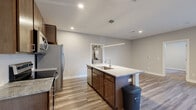 Located at 555 W 5th Ave in Columbus, Ohio, this well-appointed 2-bedroom, 2-bathroom unit offers a thoughtfully designed single-level layout. The open-concept kitchen and living area serves as the heart of the home, anchored by a central island with a granite countertop, undermount sink, and a sleek pendant light fixture overhead. Rich dark-wood cabinetry pairs with stainless steel appliances, including a refrigerator, range, and microwave, while wood-look plank flooring runs throughout the main living areas, adding warmth and cohesion. The living area benefits from abundant natural light through large windows and a glass door leading to an outdoor area. The two bedrooms are comfortably sized, with the primary bedroom featuring dual windows for natural light and plush carpeting underfoot, along with access to a well-sized walk-in closet with wire shelving. The bathrooms are finished with granite-top vanities, undermount sinks, brushed nickel hardware, and tile flooring. A dedicated in-unit laundry room with a stacked washer and dryer adds everyday convenience. Two closets provide ample storage throughout the unit, completing this functional and modern living space.