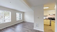 This single-floor residence offers a clean, functional layout with a neutral color palette and modern finishes throughout. The open living and dining area is anchored by durable wood-style flooring and features vaulted ceiling details, recessed lighting, and a wall-mounted thermostat. Natural light flows in through multiple windows fitted with blinds, and a glazed exterior door provides direct outdoor access, enhancing the sense of openness.

The kitchen is designed for practicality, featuring a U-shaped layout with light-toned cabinetry, dark granite-style countertops, stainless steel appliances including a gas range and dishwasher, and a single-basin sink. The kitchen connects seamlessly to the main living space.

The bedrooms are carpeted for comfort, each with large windows that invite natural light and views of the surrounding greenery. Baseboard heaters are present in both rooms, ensuring year-round comfort.

Two bathrooms serve the residence. The first includes a vanity with under-sink cabinetry, a wall mirror with overhead lighting, wood-style flooring, and a bathtub with shower. The second is a compact bathroom with a standalone shower stall, toilet, and wood-style flooring. Both bathrooms maintain a consistent, clean aesthetic that complements the rest of the home.