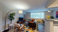 This single-floor residence showcases a cohesive mid-century modern design throughout its thoughtfully arranged living spaces. The living room serves as the heart of the home, featuring light-toned walls, smooth ceilings, and light wood-style flooring that flows throughout. A large picture window floods the room with natural light and offers views of lush greenery outside, while a vibrant geometric area rug and warm wood furnishings anchor the space with character and style.

Adjacent to the living area, a dedicated dining nook provides an intimate setting for meals, complete with a round marble-top table, curved upholstered chairs, and bold artwork that adds a rich pop of color to the corner.

The kitchen is well-equipped with crisp white cabinetry, dark granite-style countertops, and a full suite of stainless steel appliances including a gas range, microwave, and dishwasher — offering both functionality and a clean, modern look.

The bedroom is a restful retreat featuring a ceiling fan, a wide window with garden views, a built-in closet, and a soft, neutral color palette. The bathroom maintains the home's clean aesthetic with white tile, a pedestal-style sink, and white cabinetry offering practical storage. Together, these spaces form a well-balanced, stylish, and comfortable home.