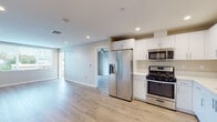 Located in the Ocean Beach neighborhood of San Diego, this single-floor residence offers a clean, modern design throughout. Light wood-style flooring runs continuously across the entire unit, creating a cohesive and airy feel.

The kitchen is well-appointed with white shaker cabinetry, a crisp white countertop, and a full suite of stainless steel appliances including a gas range, over-the-range microwave, French door refrigerator with ice and water dispenser, and a dishwasher. Recessed lighting illuminates the space, which opens directly into the main living area.

The living area is generously sized and bathed in natural light from large windows with views of the surrounding neighborhood. A ceiling fan enhances comfort, and a sliding glass door leads out to a private balcony, extending the living space outdoors.

The bedrooms are well-proportioned, each featuring light-toned walls, wood-style flooring, and ample natural light from windows with horizontal blinds. One bedroom includes a ceiling fan for added comfort.

The bathrooms are finished in a contemporary style, featuring white vanities with solid-surface countertops, large mirrors, glass-enclosed showers with tiled surrounds, and wood-style flooring. Brushed nickel fixtures and hardware complete the polished look throughout.