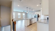 This three-story home in McDonough, Georgia offers four bedrooms, five bathrooms, and a well-planned layout spread across three floors. The entry-level hosts a two-car garage with an automatic opener and a clean concrete floor, providing generous vehicle and storage space.

The main living floor features an open-concept kitchen and living area bathed in natural light. The kitchen is outfitted with crisp white shaker cabinets, granite countertops, a subway tile backsplash, stainless steel appliances including a range and built-in microwave, and an adjacent open shelving nook. Light wood-tone flooring runs throughout, lending warmth and continuity to the space.

The upper floor houses the bedrooms, each fitted with ceiling fans, neutral toned walls, and light hardwood-style flooring. Windows with white blinds invite natural light and offer neighborhood views. The generously sized primary suite includes a walk-in closet with built-in rods and shelving. Its en-suite bathroom features a glass-enclosed tiled shower, a soaking tub beneath a bright window, and granite-topped dual vanity. Secondary bathrooms include tub-shower combinations with brushed nickel fixtures. A dedicated laundry room with full-size side-by-side washer and dryer and overhead wire shelving adds everyday convenience.