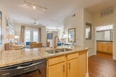 This single-floor residence at The Bristol in Memphis, Tennessee, offers a thoughtfully designed layout that balances comfort and functionality. The open-concept floor plan connects the kitchen, dining, and living areas, creating a cohesive and inviting atmosphere throughout.

The kitchen is outfitted with light maple cabinetry, granite countertops, stainless steel appliances including a refrigerator and microwave, and a double sink set into an extended peninsula. Warm hardwood-style flooring grounds the space and flows into the adjacent dining area, where a compact dining setup sits comfortably alongside the kitchen pass-through.

The living room features plush carpeting, neutral wall tones, and large windows paired with French doors that allow abundant natural light and views of the surrounding greenery. The space accommodates a generous seating arrangement and offers a bright, airy ambiance.

The bedroom area, visible in the floor plan, is privately situated and includes access to a roomy walk-in closet fitted with wire shelving and hanging rods, providing ample storage. A bathroom with a vanity and mirror completes the private quarters.

Throughout the residence, the soft color palette, carpeted living and sleeping areas, and well-placed windows contribute to a warm and comfortable living environment.