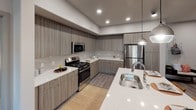 This well-designed single-floor residence offers a thoughtful layout that balances comfort and contemporary style. The kitchen is a standout feature, showcasing sleek wood-grain cabinetry, quartz countertops, stainless steel appliances including a gas range, built-in microwave, and refrigerator, along with a peninsula with an undermount sink and pendant lighting — ideal for both cooking and casual dining.

The living area is bright and welcoming, benefiting from multiple windows dressed with patterned drapes that allow natural light to filter through. Wood-look flooring anchors the space, complementing the modern yet eclectic décor.

Both bedrooms are generously proportioned with plush carpeting, large windows, and ample closet space. Each room carries a relaxed, residential ambiance enhanced by thoughtful design details and access to natural light.

The two bathrooms are finished with wood-grain vanities, white quartz countertops, large mirrors with bar lighting, and wood-look flooring — creating a clean, spa-inspired aesthetic. One bathroom features an extended double-sink vanity, while the second serves as a well-appointed full bath. Together, the spaces reflect a cohesive modern design sensibility throughout.
