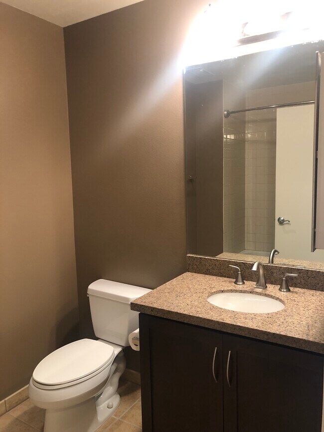 Baño completo con encimeras de granito, gabinetes de madera oscura y pisos de baldosas. - 427 9th Ave