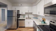 This single-floor residence offers a practical and well-organized layout designed to maximize comfort and functionality. The kitchen stands out as a highlight of the space, featuring white shaker-style cabinetry extending to the ceiling, light granite countertops, a classic white subway tile backsplash, and a full suite of stainless steel appliances including a refrigerator, dishwasher, and range. Warm hardwood-style flooring and a single-basin sink complete the kitchen's clean, modern aesthetic.

The bedrooms are carpeted and neutral in tone, each offering generous proportions and natural light through window blinds. Louvered bifold closet doors provide ample storage in each room, with the primary bedroom featuring a notably wide double-door closet with built-in shelving and hanging rods. The living area is expansive with wall-to-wall carpet, multiple windows that invite natural light, and an open connection to the adjacent hallway.

The bathroom is efficiently laid out, featuring a tub-shower combination, a white vanity, and wood-style flooring. Throughout the unit, neutral gray walls, white trim, and consistent finishes create a cohesive and understated atmosphere.