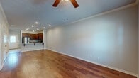 Located at 4000 S Dixieland Rd in Rogers, Arkansas, this two-story residence offers a well-designed layout with quality finishes throughout. The main level features a spacious open living area with rich hardwood flooring, crown molding, recessed lighting, and a ceiling fan, creating a bright and welcoming atmosphere. The living space flows seamlessly into the kitchen, which is appointed with warm-toned wood cabinetry, granite countertops, a large island with an undermount sink, and a full suite of stainless steel appliances including a refrigerator, range, and microwave. Tile flooring grounds the kitchen area, adding a practical contrast to the hardwood in the living space. A half bathroom on the main level features a granite vanity top with an undermount sink. The upper level houses the bedrooms, each finished with plush carpeting, ceiling fans, and ample natural light from windows. The bedrooms include closets with built-in shelving for organized storage. The bathrooms are equipped with tub-shower combinations, granite vanities, and brushed nickel fixtures. Crown molding and consistent, neutral tones throughout tie the interior together into a cohesive and comfortable living environment.