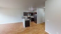 This single-floor residence in Minot, North Dakota offers a thoughtfully designed layout with clean, modern finishes throughout. The open-concept kitchen is a standout feature, showcasing rich dark cabinetry, light granite countertops, a peninsula with bar seating, and a full suite of stainless steel appliances including a range, microwave, and refrigerator. Light hardwood-style flooring flows through the kitchen and main living area, creating a warm and cohesive aesthetic. The living space opens directly to a private balcony, allowing for natural light and outdoor views. The bedrooms are carpeted for comfort, with neutral tones and ample natural light provided by generously sized windows dressed with horizontal blinds. The bathrooms are clean and functional, featuring a tub-shower combination with bright white surrounds, dark vanity cabinetry, and granite countertops consistent with the rest of the home. A dedicated in-unit laundry area with a full-size washer and dryer adds everyday convenience. The overall design is characterized by a neutral color palette, consistent finishes, and a practical floor plan that balances open living with well-defined private spaces.